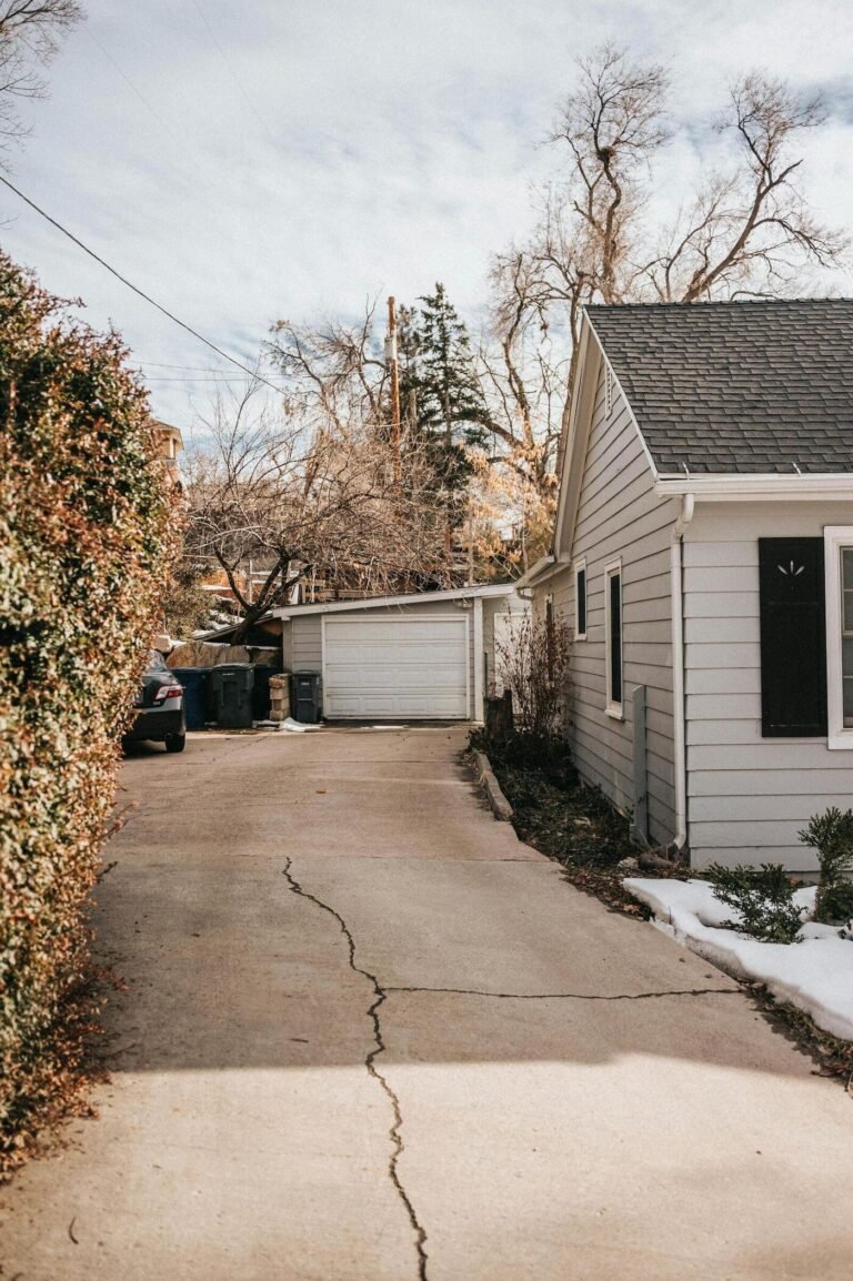 Suburban driveway with cracked pavement leading to a house